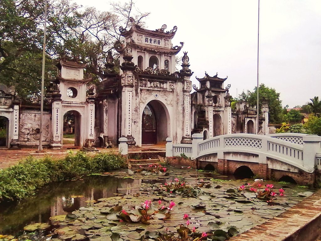 Tam quan chùa cổ với hồ sen lá xanh và cầu đá